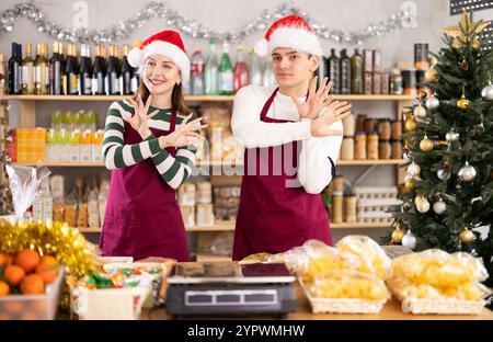 Zwei lustige Verkäufer im Weihnachtsmann führen verschiedene lustige akrobatische Moves im Supermarkt durch Stockfoto