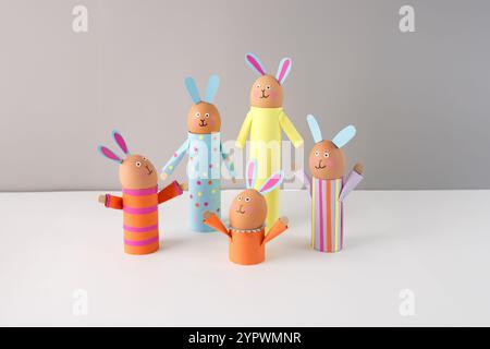 Handgemachte Osterhasen-Basteln mit farbigem Papier, Eierhalter auf grauem Hintergrund, recycelte Toilettenpapierrolle oder Papiertuch leere Röhre. Osterfeier Stockfoto