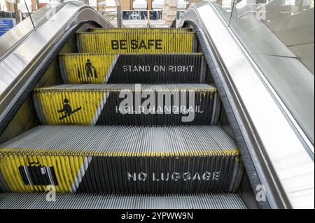 Rolltreppe am Bahnhof mit Meldung zur Trittstufe. Bitte seien Sie sicher, stehen Sie rechts und halten Sie den Handlauf. Warnschild und Warnung Stockfoto
