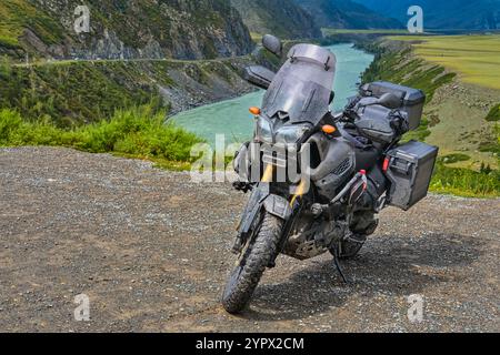 Schlammiges Motorrad im Gelände während einer wilden Fahrt in den Altai Bergen. Dreckiges Motorrad am Aussichtspunkt wartet auf Abenteuer. Stockfoto