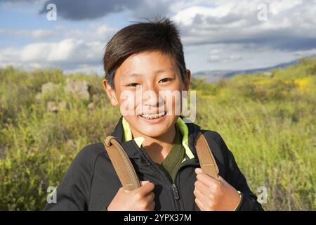 Junge, sportliche asiatische Jungen, die den Berg während des California Golden Poppy und der Goldfelder im Walker Canyon, Kalifornien, genießen und wandern. USA. Stockfoto