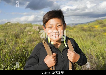 Junge, sportliche asiatische Jungen, die den Berg während des California Golden Poppy und der Goldfelder im Walker Canyon, Kalifornien, genießen und wandern. USA. Stockfoto