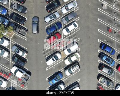 Blick von oben auf den Parkplatz im Einkaufszentrum mit verschiedenen farbigen Fahrzeugen. Leute, die zu ihrem Auto gehen und versuchen zu parken Stockfoto