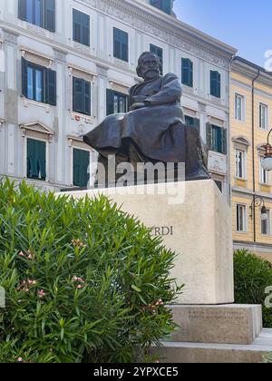 Triest, Italien - 29. Juni 2024: Giuseppe Fortunino Francesco Verdi Bronzestatue, auf weißem Steinsockel mit Blumenpflanze vor dem Gebäude fac Stockfoto