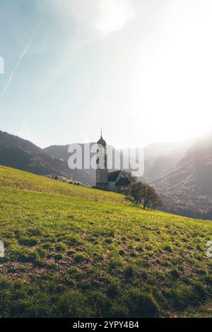 Eine typische Kirche eingebettet in eine Bergwiese, beleuchtet von einem magischen sonnigen Licht Stockfoto