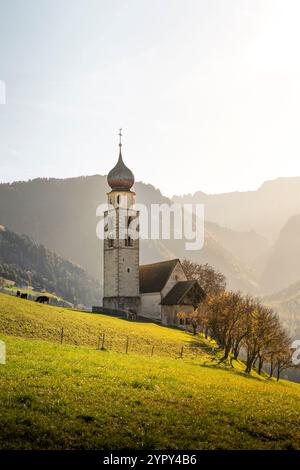 Eine typische Kirche eingebettet in eine Bergwiese, beleuchtet von einem magischen sonnigen Licht Stockfoto