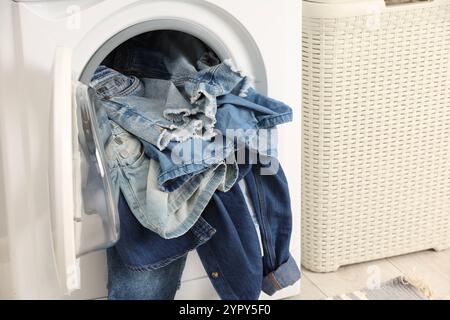 Waschmaschine mit schmutzigen Jeans und anderen Denim-Kleidern im Innenbereich Stockfoto