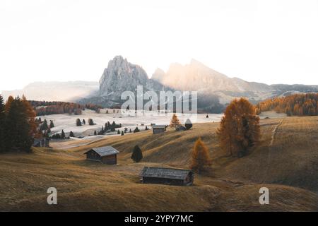 Ruhiger alpiner Sonnenaufgang: Erleben Sie die atemberaubende Schönheit von Herbstbäumen, majestätischen Bergen, lebhaften Herbstfarben und frühen schneebedeckten Gipfeln Stockfoto