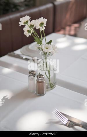 Ein elegantes Tischset mit wunderschönen Blumen und verschiedenen Zubereitungen Stockfoto