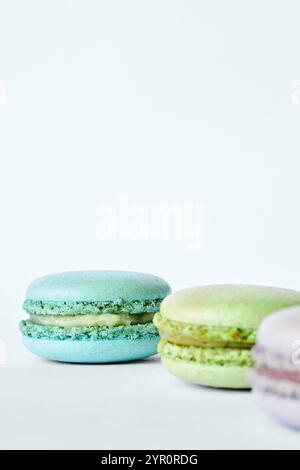 Drei bunte französische Macarons auf grauem Hintergrund, Kuchen mit verschiedenen Aromen, Minze, Apfel, Johannisbeergeschmack. Hausgemachtes Dessert, Makronen, Aquamarin, Stockfoto