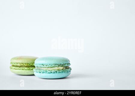 Zwei farbenfrohe französische Macarons, Kuchen mit verschiedenen Aromen, Minze- und Apfelgeschmack. Hausgemachtes Dessert, Makronen Aquamarin, grüne Farbe auf grauem Hintergrund Stockfoto