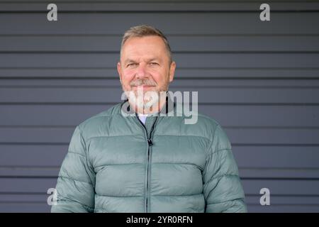 Ein Mann mittleren Alters mit einem gepflegten grauen Bart und einem sanften Lächeln blickt direkt in die Kamera. Stockfoto