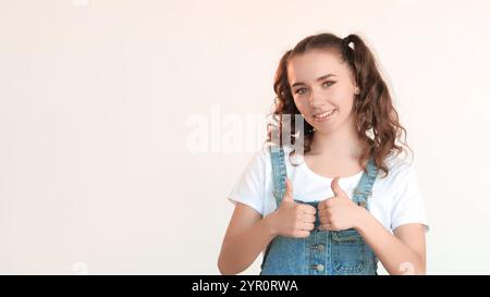 Ja-Geste. Perfekte Wahl. Bewunderung unterstützt Super-Idee wie Signal Congratats Zeichen. Amüsantes, aufgeregtes Teenager-Mädchen, das die Daumen hoch zeigt und isoliert auf weißem Kopierraum lächelt. Stockfoto