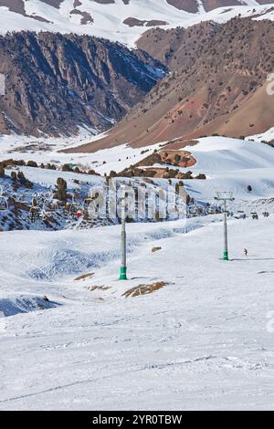 Die Menschen fahren mit einem Sessellift auf den Gipfel des Berges. Winteraktivität im Skigebiet. Tschunkurchak, Kirgisistan, Kirgisiya. Skiliftstock, Schnee auf dem Berg Stockfoto