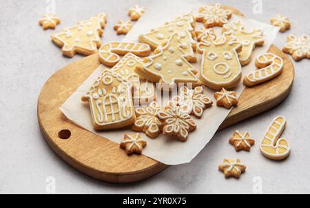 Weihnachtskekse mit Puderzucker, die weihnachtsbäume, Rentiere, Schneeflocken, Lebkuchenhäuser und Zuckerstangen auf Holzbrett darstellen Stockfoto