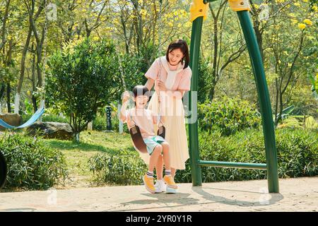 Mutter und Sohn schaukeln im Park Stockfoto