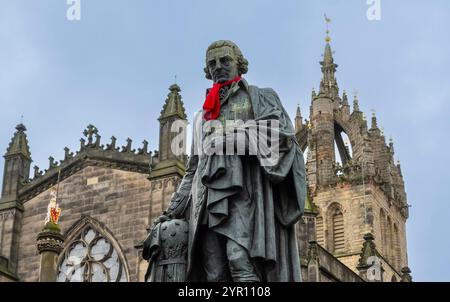 Edinburgh, Großbritannien. November 2024 30. Edinburgh, Schottland Rote Schals sind auf einigen der berühmten Statuen der Altstadt von Edinburgh zu sehen, darunter Adam Smith und James Braidwood (1800–1861). Das Bild zeigt den Zustand von Adam Smith, Statue von Adam Smith, dem „Vater der Wirtschaft“ und Autor des bahnbrechenden „The Wealth of Nations“, der 1776 veröffentlicht wurde, dem Jahr, als die USA die Unabhängigkeit erklärten. Die Bronzestatue befindet sich vor der St. Giles Cathedral auf der Royal Mile Picture von phil wilkinson/Alamy Live News Stockfoto