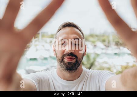 Ein lächelnder Mann mit Bart und geschlossenen Augen macht Selfie bei einer Yachtansicht Stockfoto