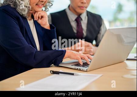Ein Bild der Nahaufnahme: Zwei Geschäftsleute sind im Meeting und schauen sich einen Laptop an, während sie über die Arbeit diskutieren, Brainstorming machen und Ideen austauschen. Stockfoto