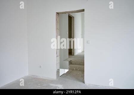 Leeres Apartment mit weißen Wänden und Betonboden wird renoviert. Innenraum des im Bau befindlichen Gebäudes Stockfoto