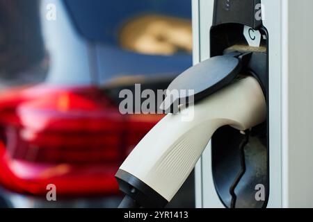 Nahaufnahme des Aufladens eines Elektrofahrzeugs auf dem öffentlichen Bahnhof in der Stadtstraße. EV-Fahrzeug mit eingestecktem Kabel zum Aufladen der Batterie. Nachhaltig und umweltfreundlich Stockfoto