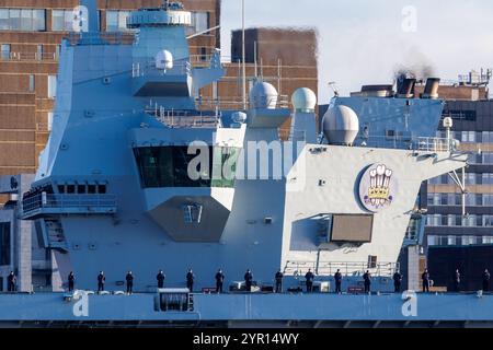 Der Flugzeugträger der Royal Navy HMS Prince of Wales kommt in Liverpool an, mit der Besatzung an Deck und der berühmten Skyline der Stadt hinten Stockfoto