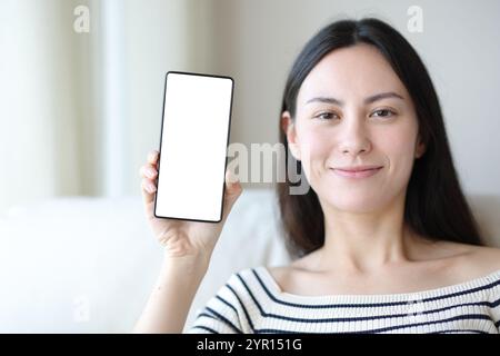 Vorderansicht einer asiatischen Frau mit leerem Telefonbildschirm zu Hause Stockfoto