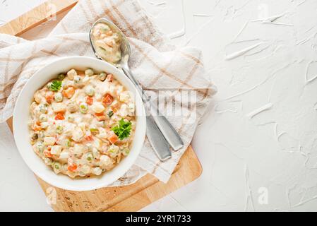 Schüssel mit russischem Salat oder olivier- oder französischem Salat mit Gemüse und Ei mit Mayonnaise auf dem weißen Tisch aus nächster Nähe Stockfoto