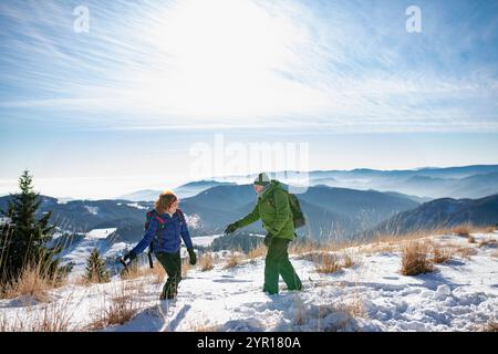 Aktive Senioren, die Schneeballkampf haben. Romantische Winterwanderung für ein älteres Paar in den schneebedeckten Bergen. Stockfoto