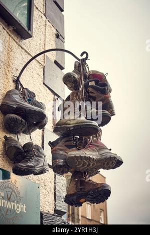 Eine Ausstellung alter Wanderschuhe, die vor dem Wainwright Pub in Keswick an einem Haufen hängen Stockfoto