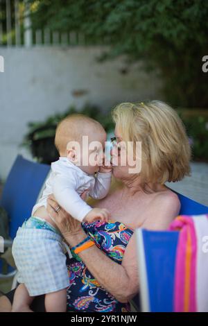 Großmutter küsst Enkel am Pool an Deck Stockfoto
