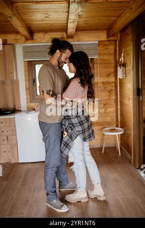 Junger Mann und Frau, die sich im Wohnzimmer umarmen. Stockfoto