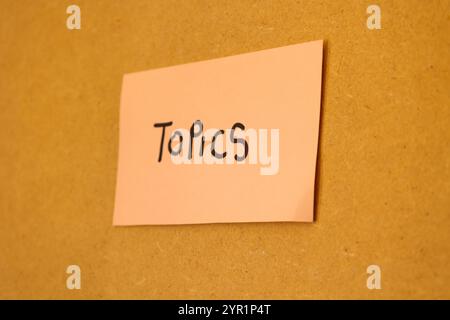 Nahaufnahme einer rosafarbenen Notiz, die auf einer Tafel mit einer schriftlichen Nachricht zu Themen, Notizen und Themen hängt Stockfoto
