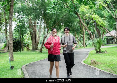 Glückliches Paar Joggen in einem üppigen grünen Park, der Gesundheit und Wellness durch Outdoor-Übungen und frische Luft fördert Stockfoto