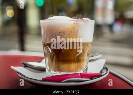 Cappuccino serviert in einem Glas auf einem Pariser Kaffeetisch Stockfoto