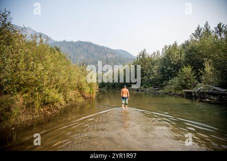 Der Mann der First Nations weht im flachen Fluss und verbindet sich mit dem Land Stockfoto