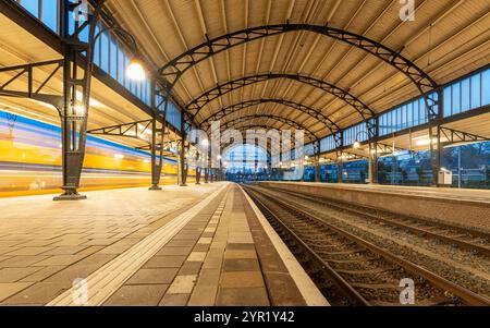 Lange Exposition des niederländischen Zuges, der durch den Bahnhof Haarlem fährt und mit dem Zug in den Niederlanden fährt Stockfoto