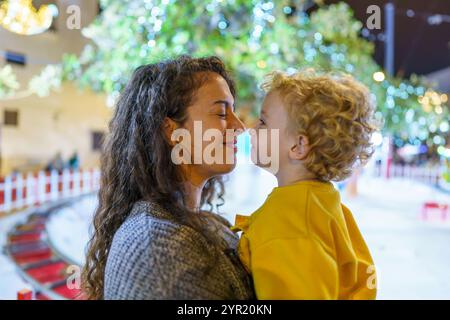 Mutter und Sohn reiben Nasen, genießen weihnachtsstimmung und Winterferien auf einem dekorierten Markt im Freien Stockfoto