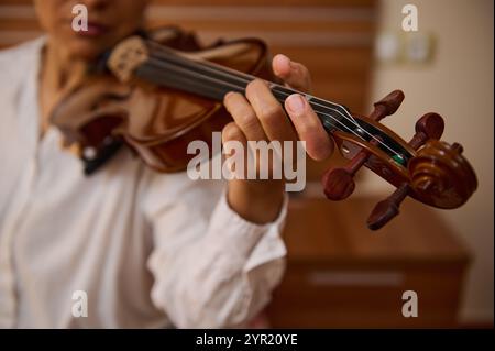 Eine detaillierte Ansicht der Hand eines Musikers, die anmutig auf den Violinsaiten positioniert ist, zeigt Präzision und künstlerischen Ausdruck. Die warmen Töne sind emphasi Stockfoto