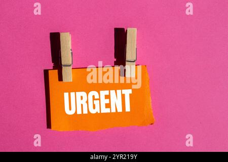 Dringende Nachricht geschrieben auf gerissenem, gerissenem orangenem Papierstück mit rosa Hintergrund. Konzeptionelles dringendes Wortsymbol. Kopierbereich. Stockfoto