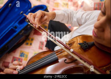 Ein detaillierter Blick auf die Hände eines Musikers, der eine Geige spielt, zeigt Geschick und Finesse. Der Fokus liegt auf Bogen und Saiten, die die Kunstfertigkeit i hervorheben Stockfoto