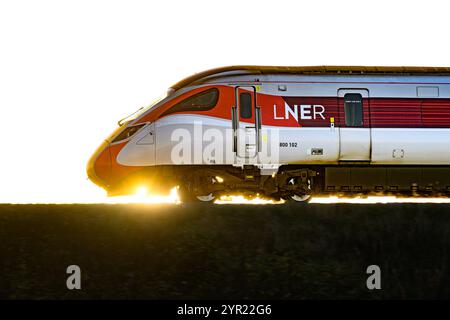 Ein LNER Azuma Train (800102), der von Einem Sonnenuntergang beleuchtet wird, während er zwischen Dalmeny und Edinburgh Gateway Stations in Schottland (Großbritannien) fährt Stockfoto