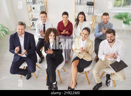 Glückliche, vielfältige Büromitarbeiter applaudieren, dem Team zu geschäftlichen Leistungen gratulieren und großartige Arbeit leisten Stockfoto