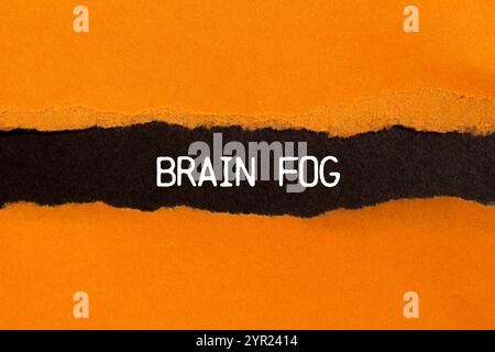 Hirnnebel-Nachricht auf gerissenem, gerissenem orangefarbenen Papier mit schwarzem Hintergrund. Konzeptionelles Hirnnebelsymbol. Kopierbereich. Stockfoto