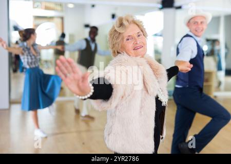 Ältere Frau und jüngerer Mann tanzen Schaukel im Studio Stockfoto