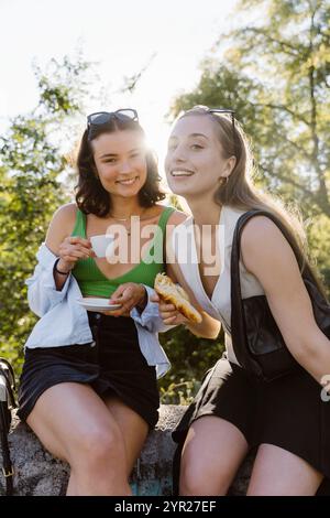 Porträt lächelnder Freundinnen, die Kaffee und Snacks trinken Stockfoto