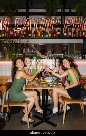 Seitenansicht von glücklichen Freundinnen, die im Restaurant Getränke trinken Stockfoto