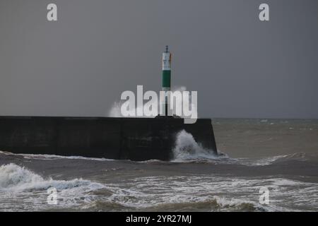 Aberystwyth Wales UK Wetter 2. Dezember 2024. Ein kalter, stürmischer Wintermorgen an der walisischen Küste, große Wellen krachen über die Seeschützung und Hafenlicht mit rosa Himmel über der Küste, Credit: mike davies/Alamy Live News Stockfoto