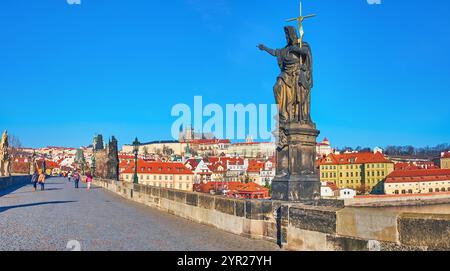 Historische Statue des Heiligen Johannes des Täufers auf der Karlsbrücke vor den roten Dächern der Mala Strana und des Veitsdoms, Prag, Tschechien Stockfoto