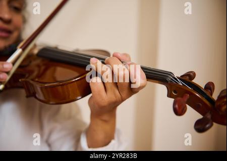 Ein detaillierter Blick auf die Hände eines Musikers, der fachmännisch Geige spielt. Das Bild vermittelt ein Gefühl von Kunst, Können und Hingabe an die Musik und zeigt die Intr Stockfoto